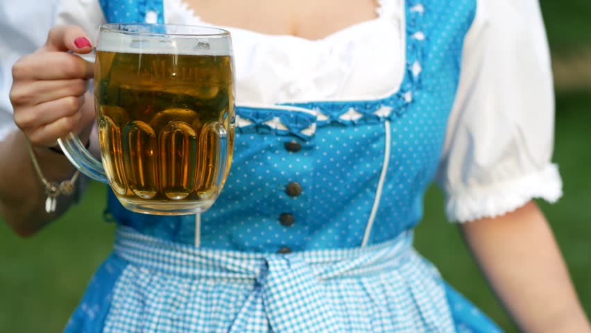Young woman in blue bavarian dirndl celebrating oktoberfest. Close up