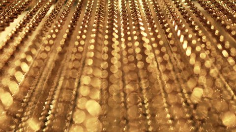 Slow, smooth movement of long gold chains. Uniform swing. Gold background for relaxation. Meditation. Relax. Texture for soothing. Glitter. View from bottom to top. Blurred Stock Video