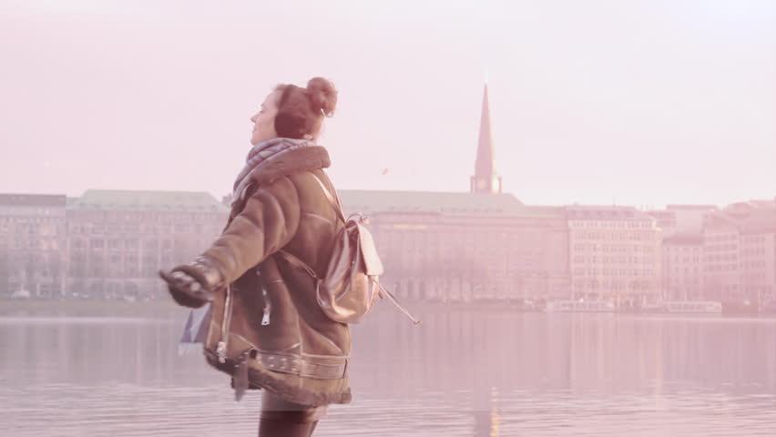 Woman spinning and enjoying first snowing with raised arms at Alster Lake in Hamburg city, Germany