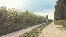 beautiful sweet girl in a blue dress and hat running toward camera on a field of sunflowers , woman enjoying summer day, countryside style, lifestyle slow motion video shooting by handheld gimbal
