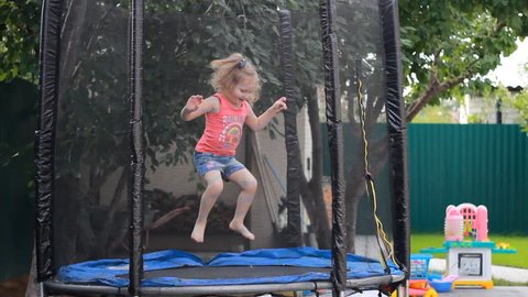 Child girl jumping on a trampoline and playing in a country house. Games for children.