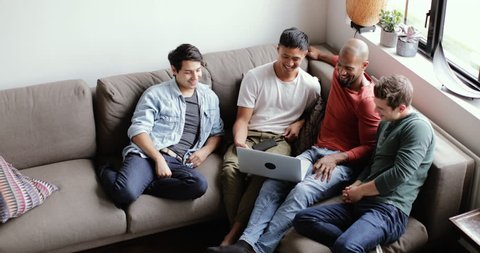 Overhead shot of group of male friends watching a video on laptop