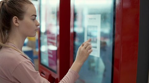 Close-up shot of a beautiful woman using digital self-service kiosk to choose and order food. Unhealthy eating, buying fast food on weekends.