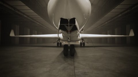 Private jet in the hangar. Camera backing up and lights gradually turning on.
