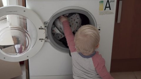 Helpful Toddler Putting Washing in Washing Machine