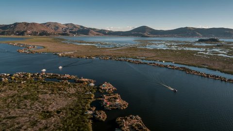 Aerial view of Floating Island Uros ( Isla de los Uros ), Lake Titicaca, filmed by drone at sunset, Peru