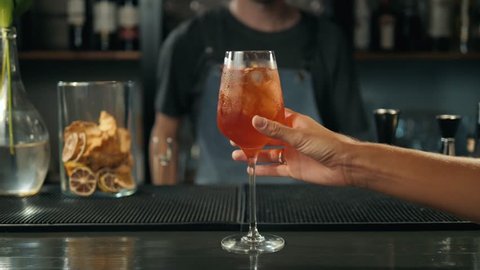 Woman hands toasting with aperol spritz cocktails, woman in bar take alcohol from bartender
