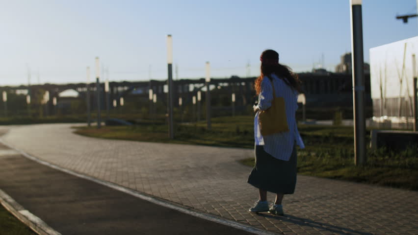 Hipster woman walking in park during sunset