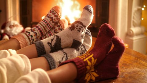 Closeup 4k footage of family with child wearing warm wool socks lying by the fireplace on Christmas eve