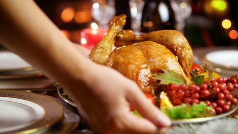 Closeup 4k video of young woman putting dish with baked chicken on dinner table served for Christmas