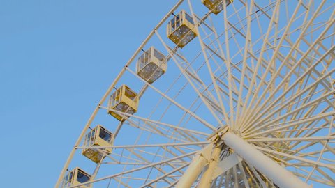 Ferris wheel shot against blue sky. Warm colors, daylight.
