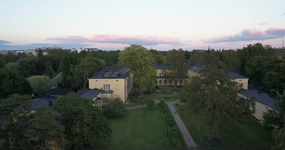4K summer sunset aerial video of Helsinki Lapinlahti historical mental hospital completed in 1841, not in operation from 2008, woods area around it, in the capital of Finland Suomi, northern Europe