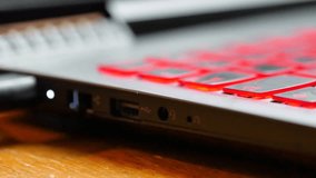 Connecting a USB key to a gaming laptop computer that has a keyboard with red lights. The plug is also red in colour.