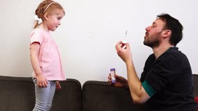 A dad blows soap bubble for his cute daughter.