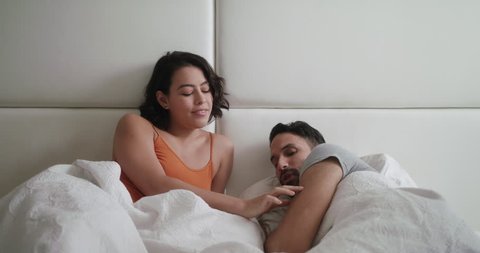 Wife trying sexual approach to bored husband in bed. Angry man refusing to have sex with woman and going back to sleep. Relationship problems for married people at home