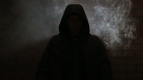 The hooded man in the smoky room near brick wall HD