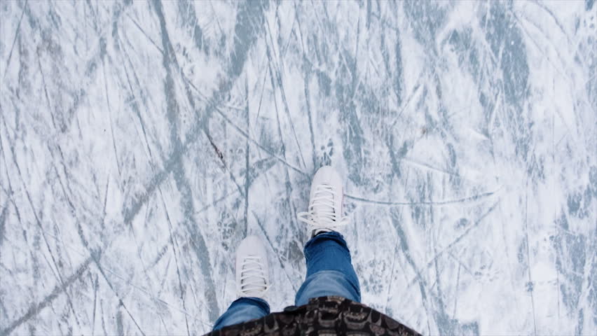 Legs teenage girl which making moving skating on rink in winter. Young woman skating on ice with figure skates outdoors in the snow