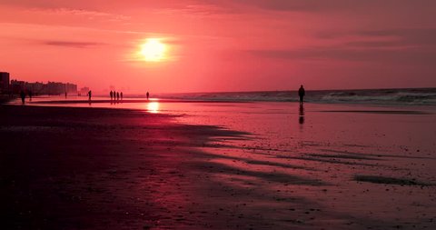 Woman walking on the beach during a sunrise in Myrtle Beach, South Carolina.