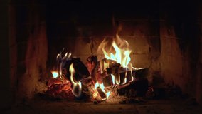 A looping clip of a fireplace with medium size flames. red fire coals warm hearth ambiance