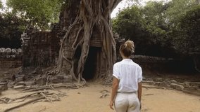 Young woman running in ancient temple discovering old ruins and different cultures at sunset time entering through temple gate exploring Cambodia. People travel Slow Motion 