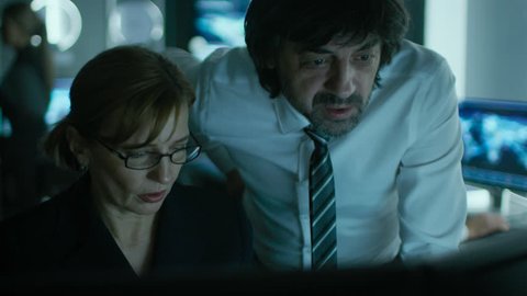 IT Professional working on Personal Computer in System Control Room. They Have Work Optimization Discussion and Agree on Strategy. Shot on RED EPIC-W 8K Helium Cinema Camera.