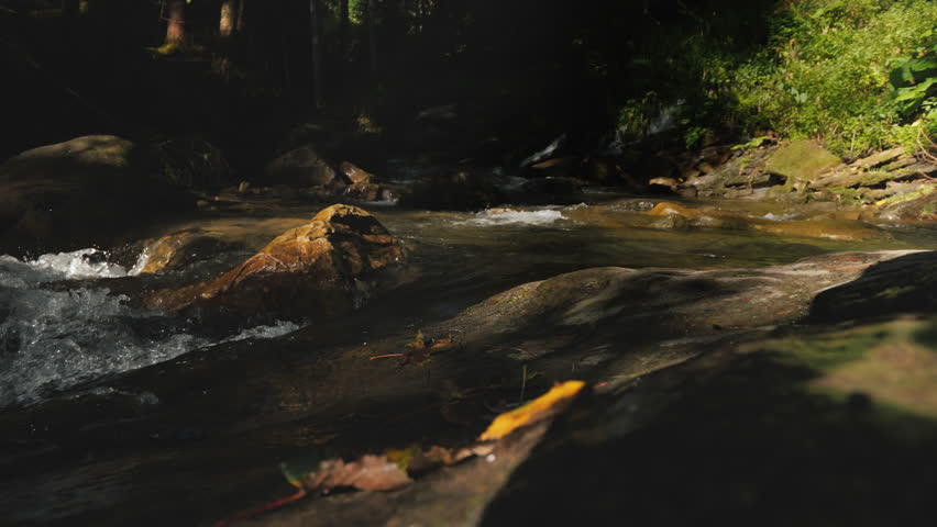 A traveler in hiking boots passes through slippery stones. Only the legs are visible