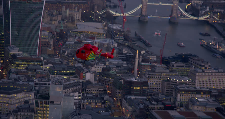 Aerial shot of London's Air ambulance above the Central London. River Thames, Tower Bridge and HMS Belfast ship in the background. Royalty-Free Stock Footage #1015990204
