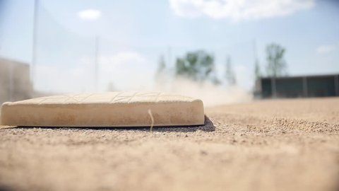 A close up slow motion show of dust and sand flying over first base at a baseball field.