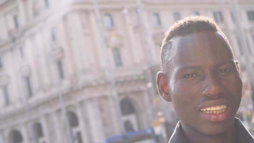 Happy amarican african youg man smiling at camera in the street