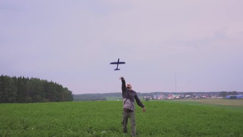 A happy family. The boy on his father playing with an airplane toy in field