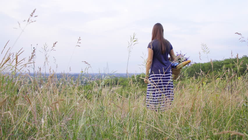 young girl climbs the hill and collects a bouquet of wildflowers