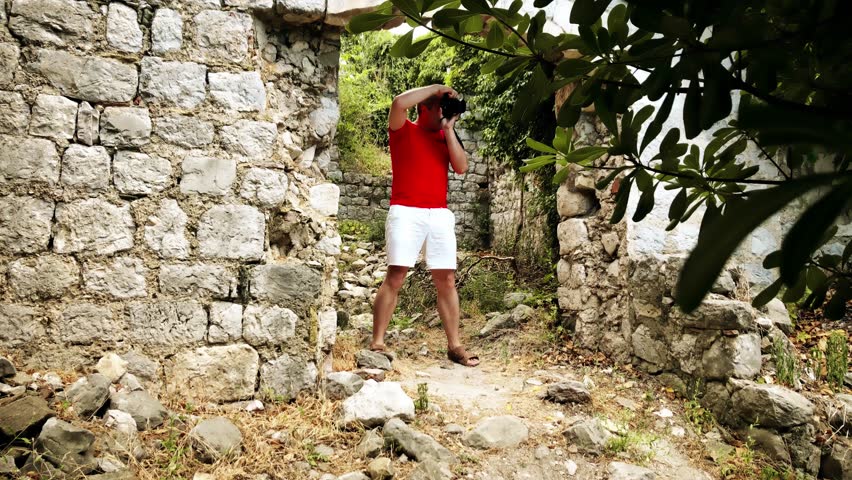 Photographer in red tshirt takes photo of ancient ruins on vacation