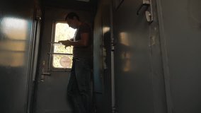 the man silhouette is standing on the train Railway carriage holding a smartphone and . slow motion video. man writes messages in the smartphone in the train social media. man lifestyle with