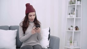 Happy modern Asian young woman talking on video chat and lying on sofa at home. Smiling hipster girl making self portrait on her telephone at home. Lifestyle woman at home concept.  