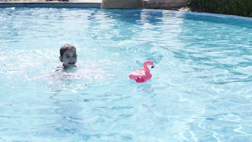 little girl is playing in the water. the child is having fun and splashing in the pool. Slow motion