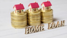 Conceptual clips of HOME LOAN word with golden coins and miniature house model.