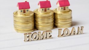 Conceptual clips of HOME LOAN word with golden coins and miniature house model.