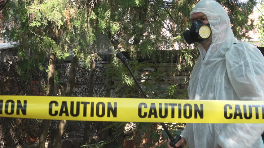 Man with protective mask in white suit with sprinkler spraying prevention disease in nature garden,Handheld camera Balanced Steady shot 