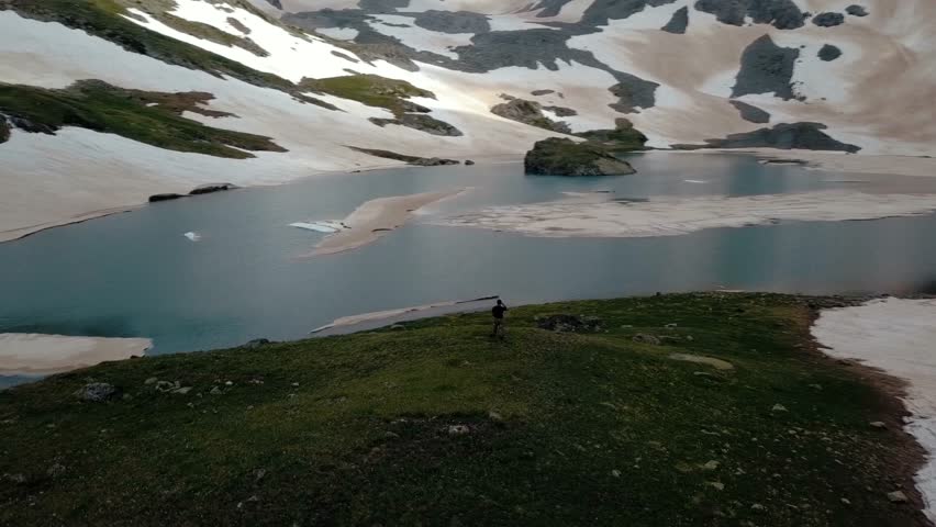 A male mountain climber is calling via satellite telephony with the very top of a snow-capped mountain and an inaccessible wildlife connection. Airshot 4K.