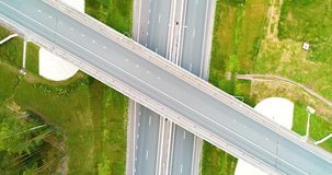 Aerial view of highway in city. Cars crossing interchange overpass. Highway interchange with traffic. Aerial bird's eye video of highway. Expressway. Road junctions. Cars in motion. Top view.
