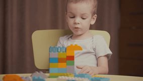 Footage little happy boy playing with colourful blocks of a constructor at home. 4k video