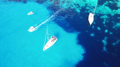 Aerial drone bird's eye view video of iconic tropical and exotic caribbean paradise bay with turquoise clear ocean visited by sail boats