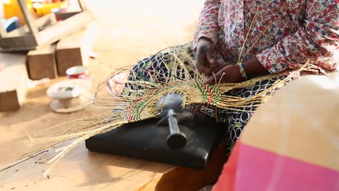 African Art. A woman weaves a fan in a marketplace in Ghana.