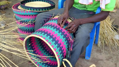 African Art. A man weaves baskets and hats in a marketplace in Ghana.