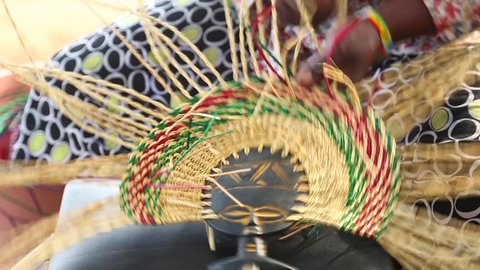 African Art. A woman weaves a fan in an art marketplace in Ghana.