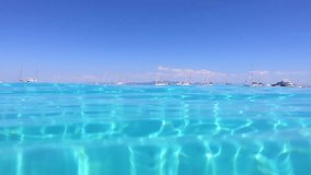 Underwater video of tropical paradise turquoise exotic beach of Voutoumi with sail boats docked in island of Antipaxos, Ionian, Greece