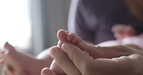 Crop view of young mom doing foot massage to her newborn baby