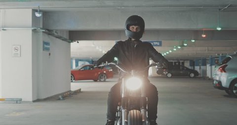 Motorbiker riding on a motorcycle in the parking lot in the city. Biker rides a vintage custom motorbike from 1970s in the garage. 4K video shooting by handheld gimbal Stock Video