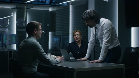 Male and Female Special Service Agents Interrogate Young Suspect in Cyber Crimes, Officer Looses Temper and Threatens Accused while Questioning. Dark Interrogation Room. Shot on RED EPIC-W 8K Camera.