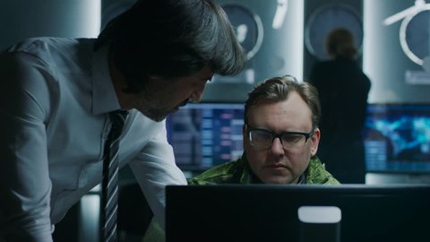 Government Chief of Cyber Security Agent Consults Military Officer who Works on Computer. Specialists Working on Computers in System Control Room. Shot on RED EPIC-W 8K Helium Cinema Camera.